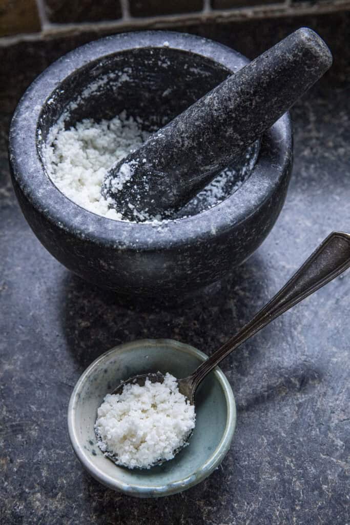 Sticky rice paste in a stone mortar and pestle and in a small bowl with a spoon.