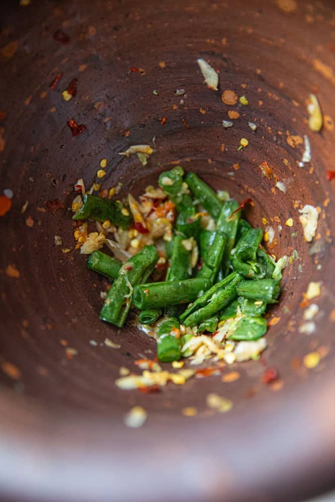 pounding garlic and chilies for som tum pu pla ra
