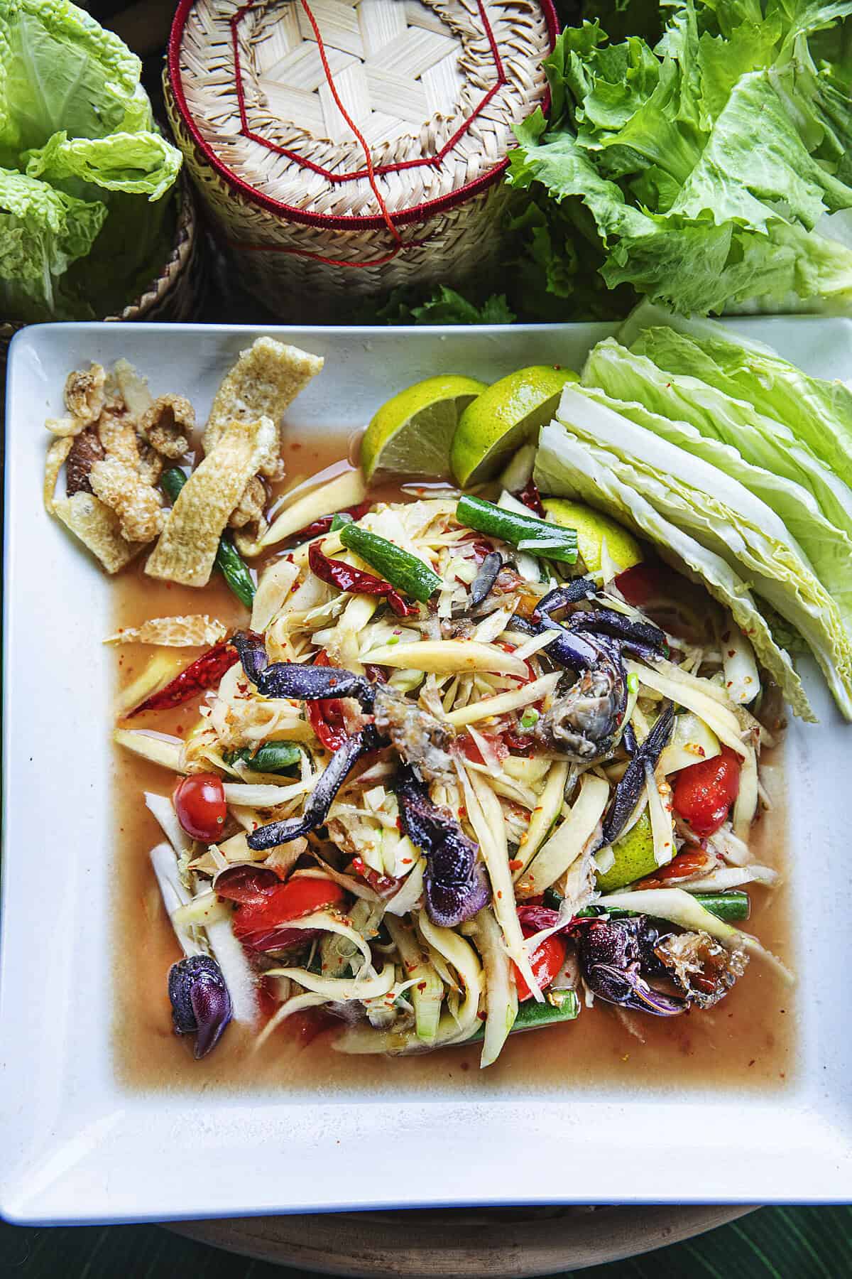 Finished som tum pu pla ra served with sticky rice and veggies.