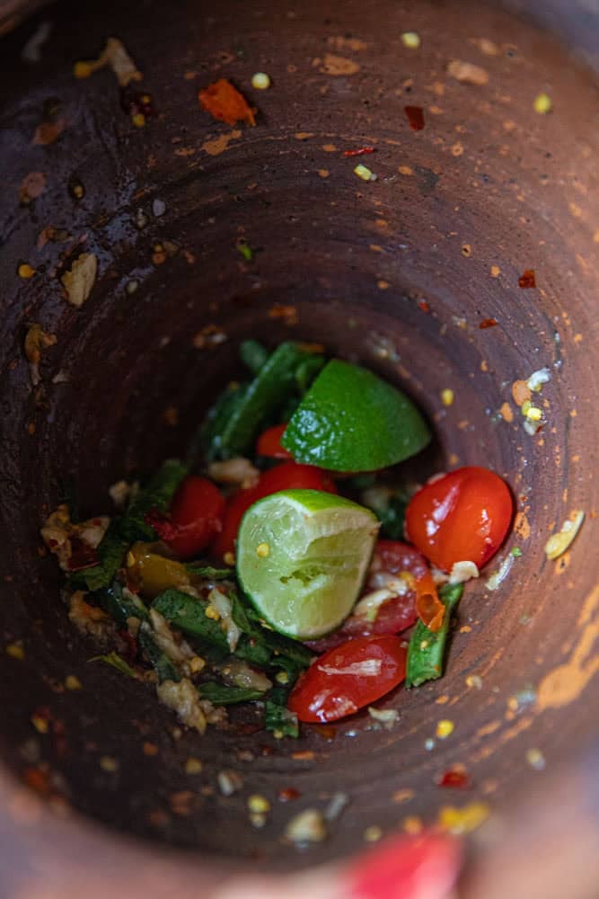 Pounding lime wedges and tomatoes for som tum pu pla ra.
