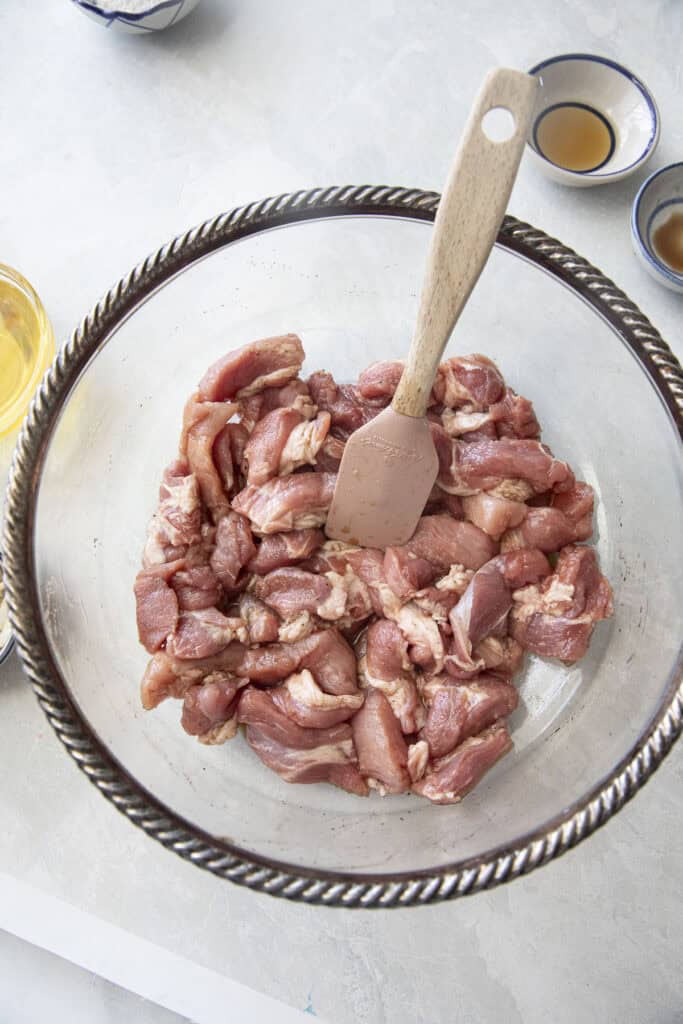 Seasoning pork with fish sauce, oyster sauce, sugar, and pepper for Moo Tod.