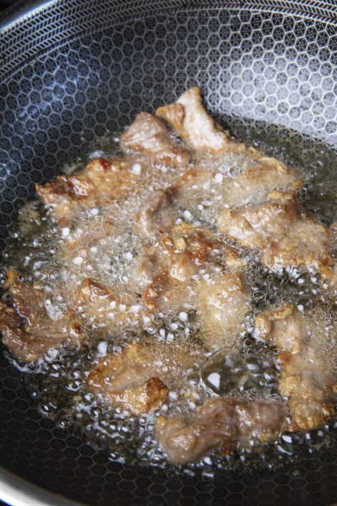 Frying Moo Tod pork in hot oil until golden brown and crispy.