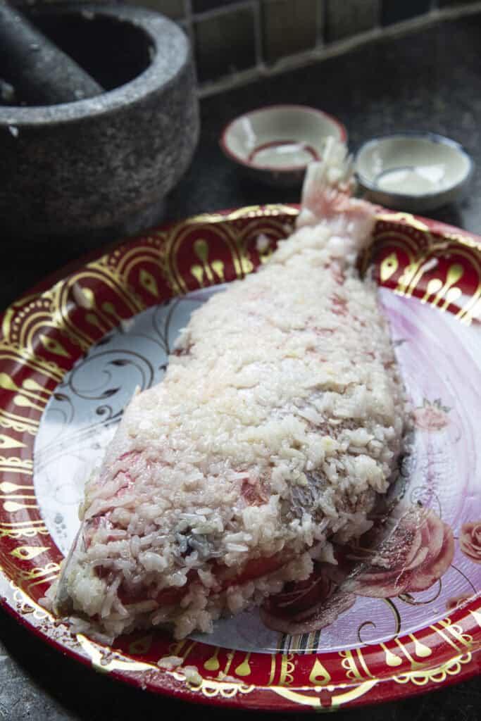 Whole fish coated with rice and garlic mixture before fermenting Pla Som.