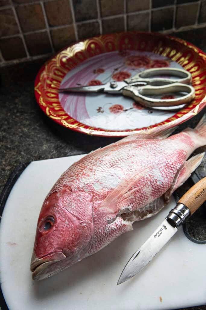 Fresh whole tilapia prepared for Pla Som fermentation on a cutting board.