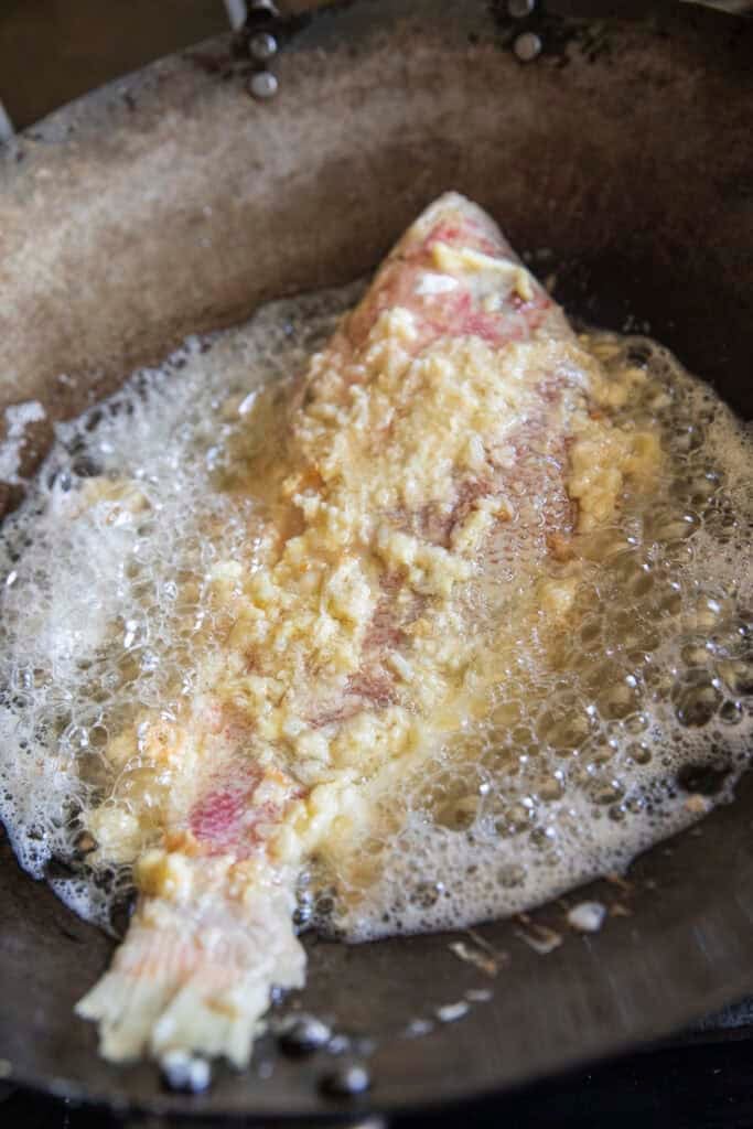 Fermented Pla Som frying in hot oil until golden and crispy.