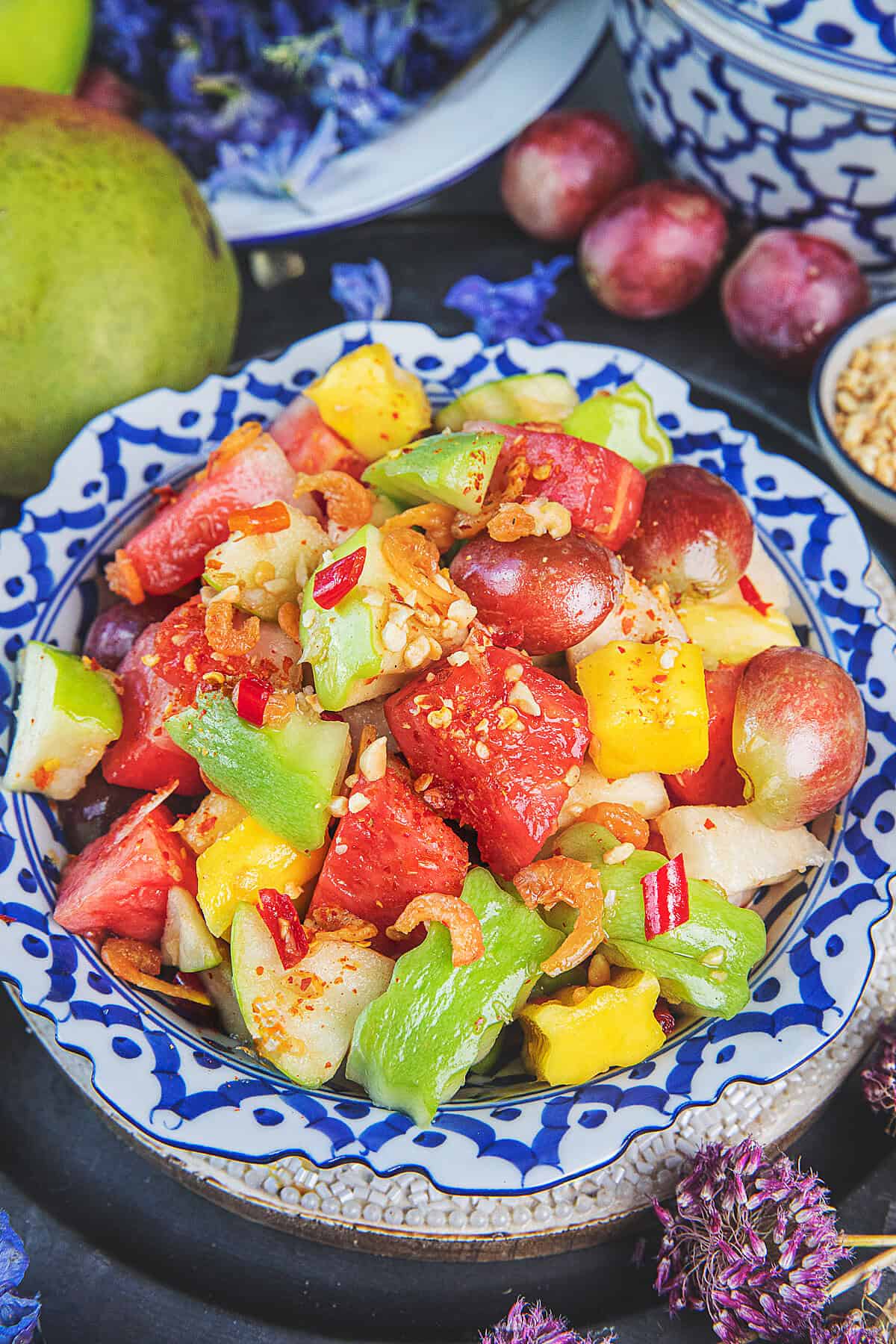 Thai fruit salad som tum fruit with mango watermelon pineapple and peanuts.
