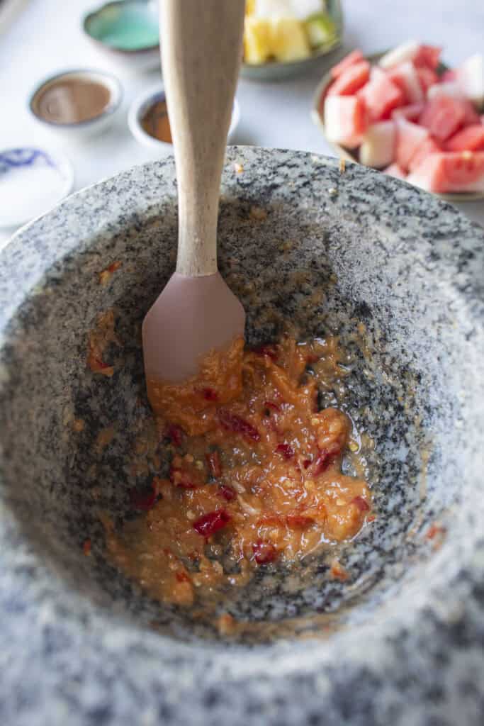 Making thai som tum dressing in a mortar pestle.