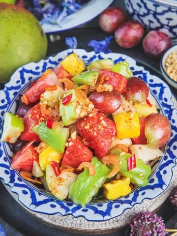 thai fruit salad som tum pol la mai served on thai patterned plate.