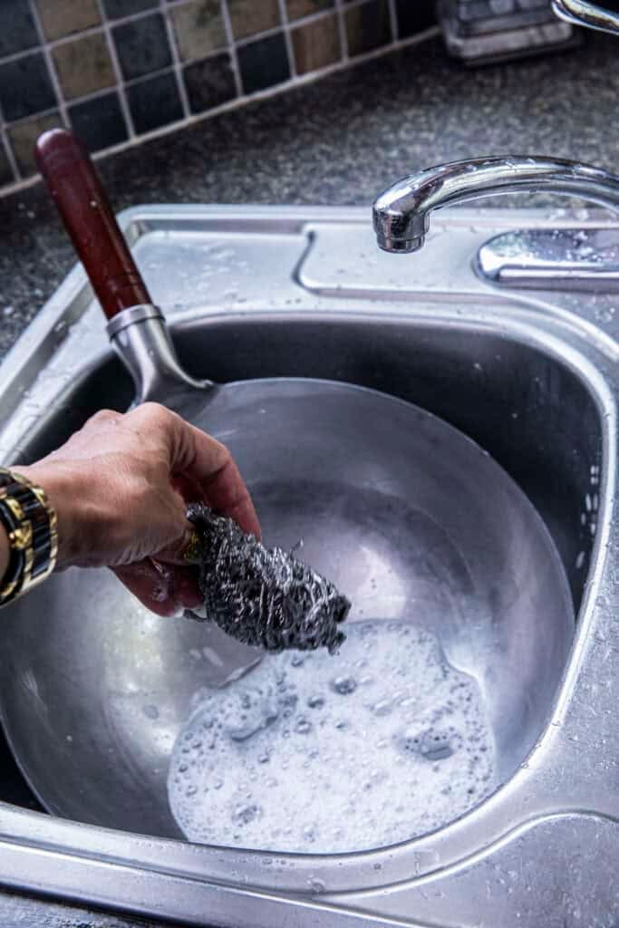 Washing a new carbon steel wok with soap and water before seasoning.