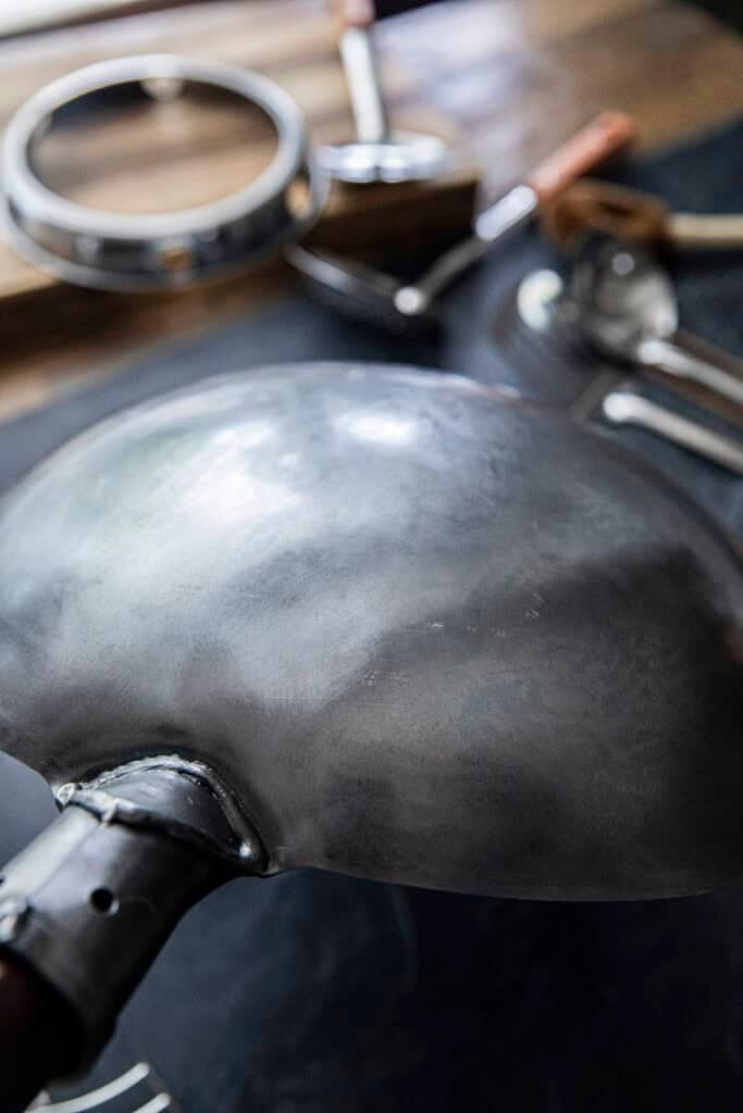 Close-up bottom view of a carbon steel wok before seasoning.