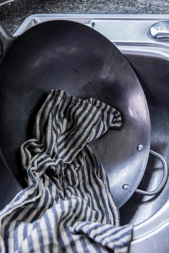 Towel drying a new carbon steel wok with soap and water before seasoning.