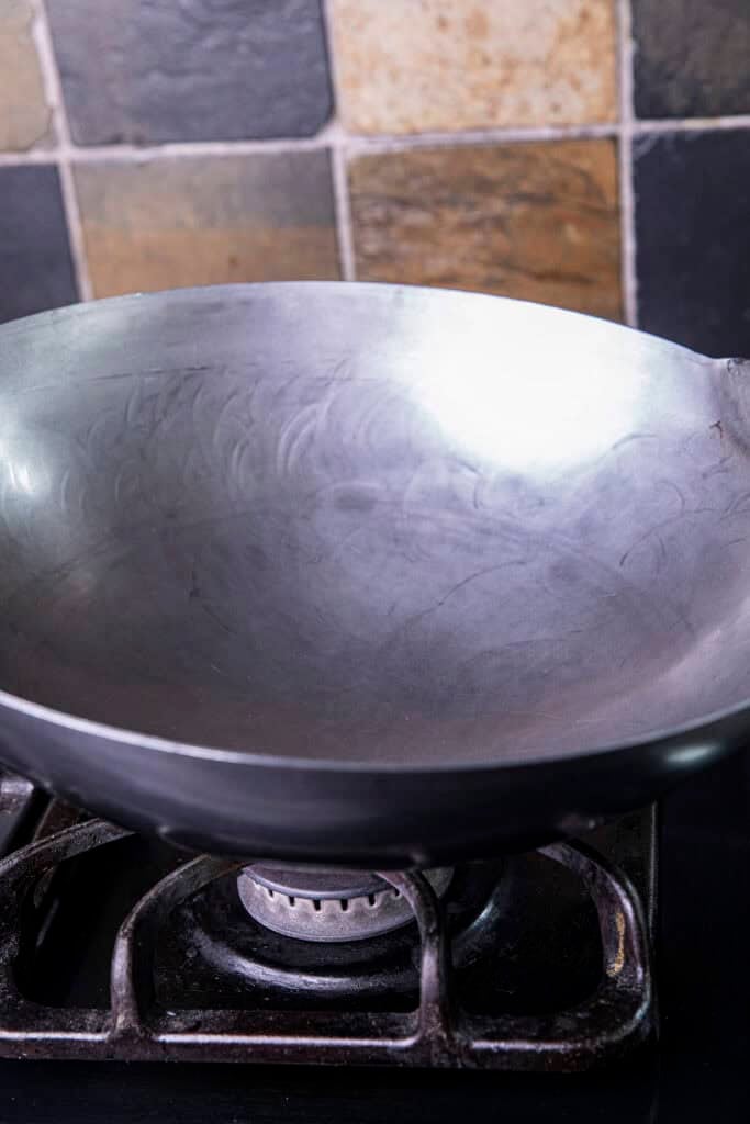 Heating a brand new carbon steel wok over a gas burner before adding oil