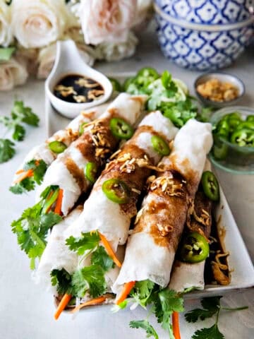 Thai fresh spring rolls, Poh Pia Sod, topped with sweet savory sauce, fried shallots, and sliced chilies.