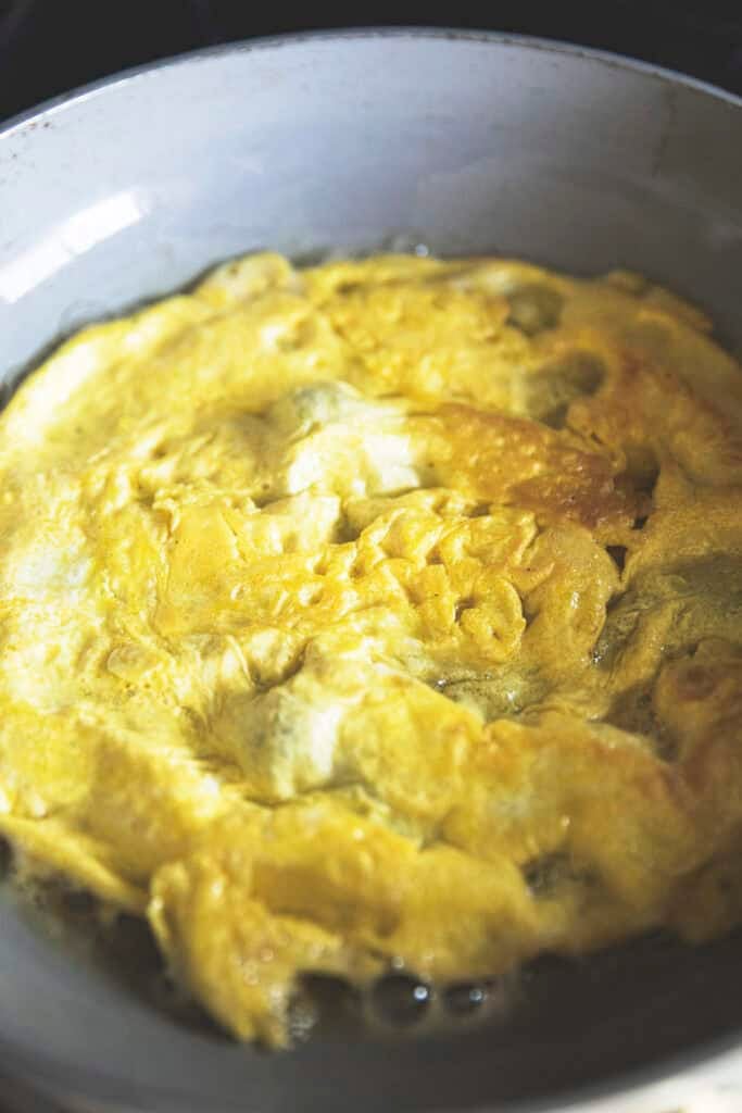 Omelette cooking in a pan for Thai fresh spring roll filling.