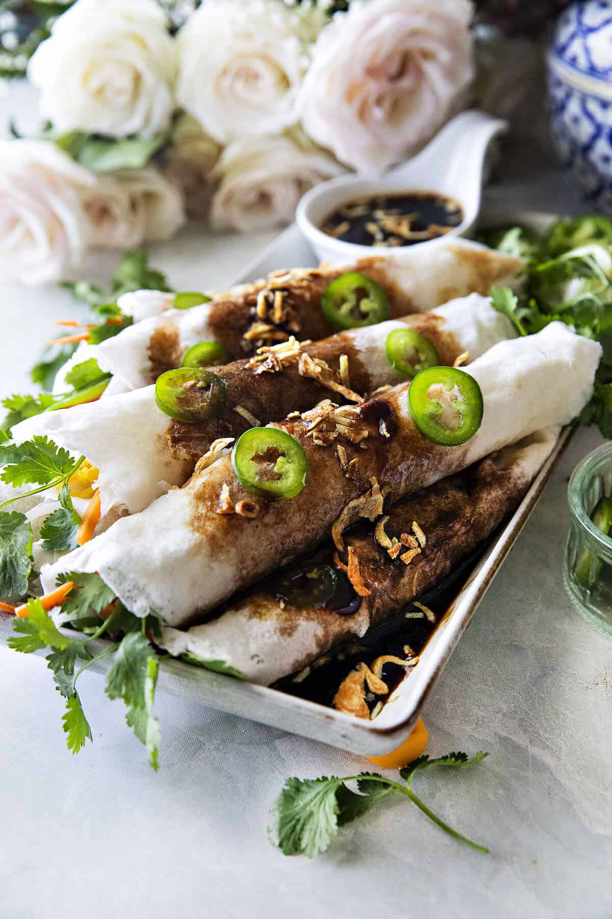 Thai fresh spring rolls, Po Pia Sot, topped with sweet savory sauce, fried shallots, and sliced chilies.
