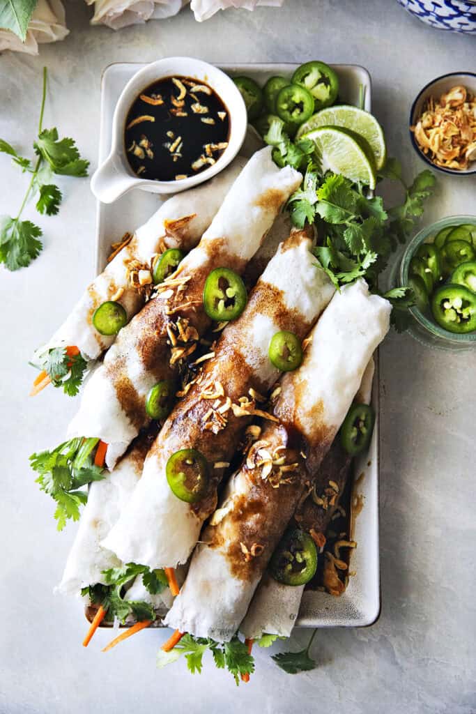 Thai fresh spring rolls, Po Pia Sod, topped with sweet savory sauce, fried shallots, and sliced chilies.
