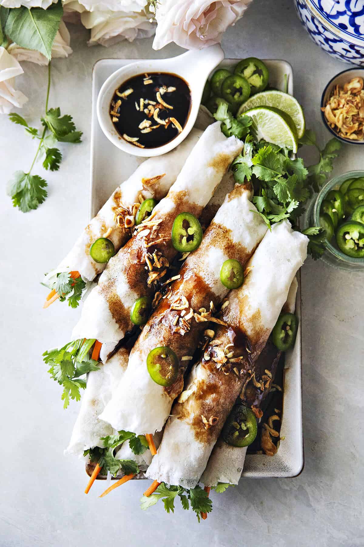 Thai fresh spring rolls, Po Pia Sod, topped with sweet savory sauce, fried shallots, and sliced chilies.