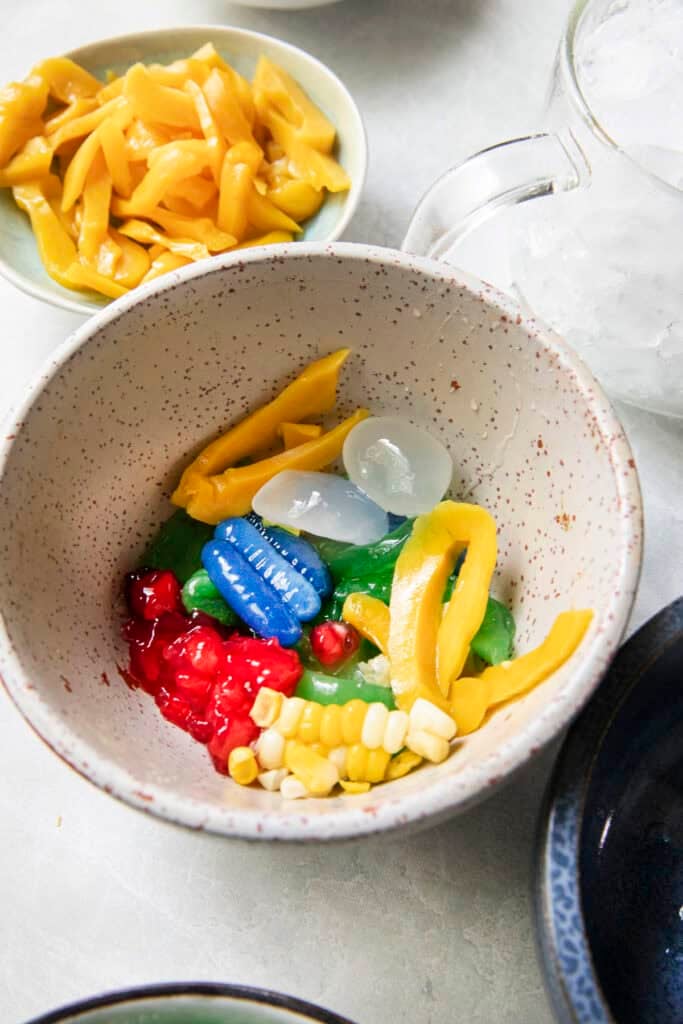 Ruam Mit toppings including sliced jackfruit, palm fruit, sweet corn, and colorful tapioca sweets.