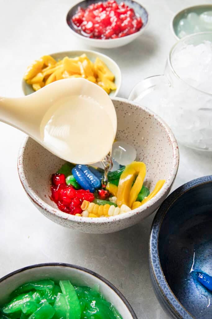 Colorful Ruam Mit toppings arranged in a bowl before adding coconut milk and crushed ice.