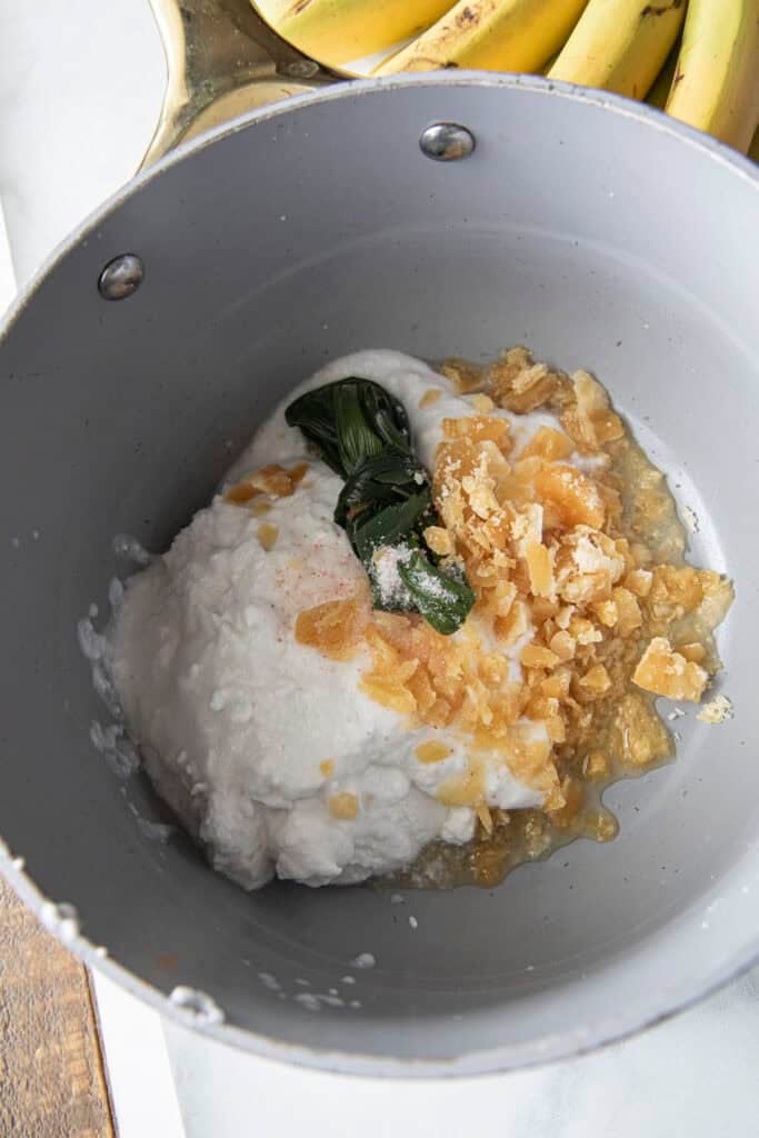 Coconut milk, palm sugar, pandan leaves, and salt in a saucepan.