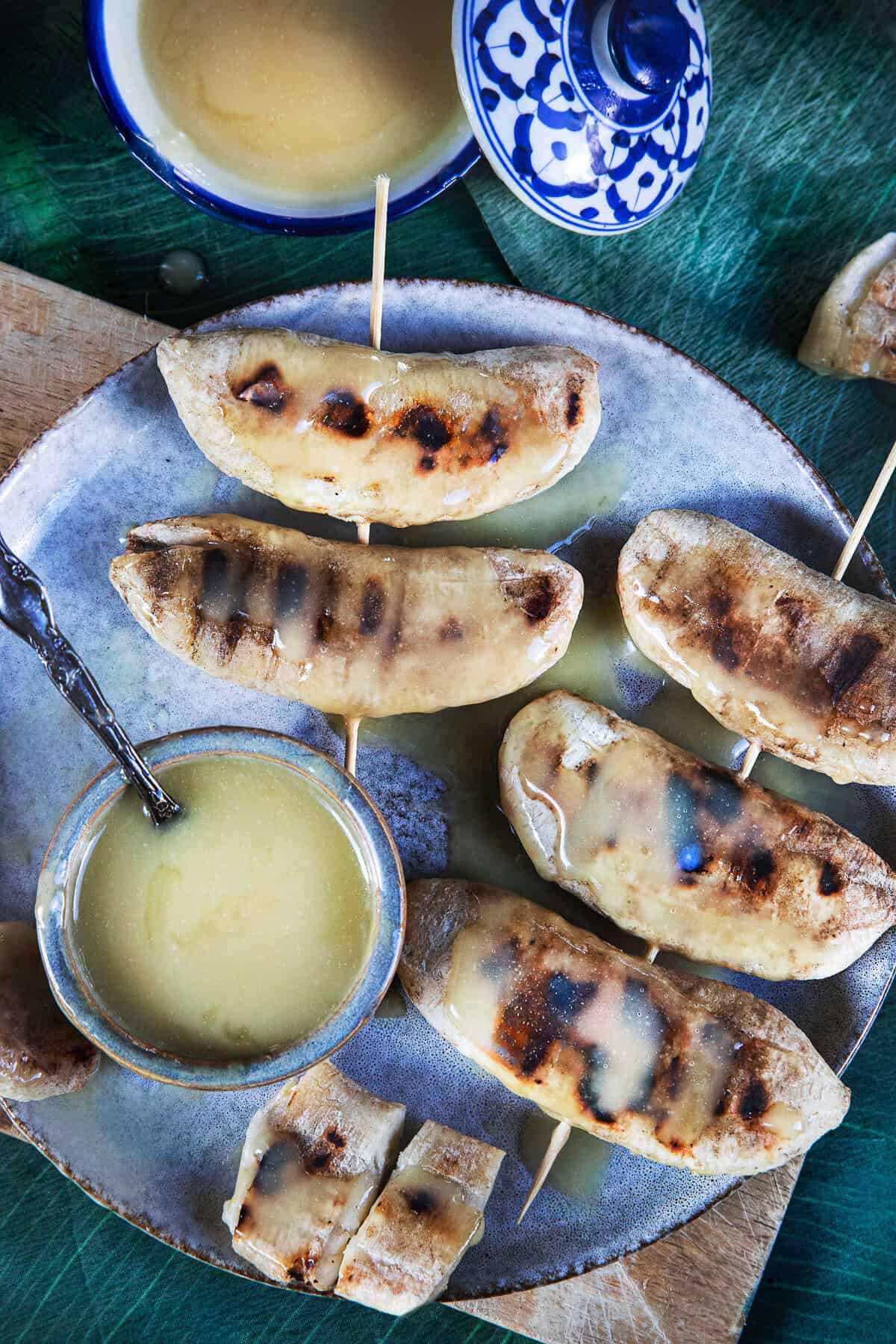 Grilled Nam Wa bananas with caramelized grill marks and coconut sauce.