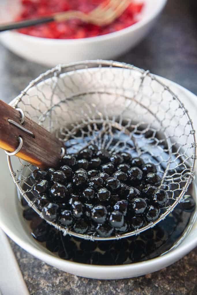 Cooked black tapioca pearls draining before adding to Nam Khaeng Sai.