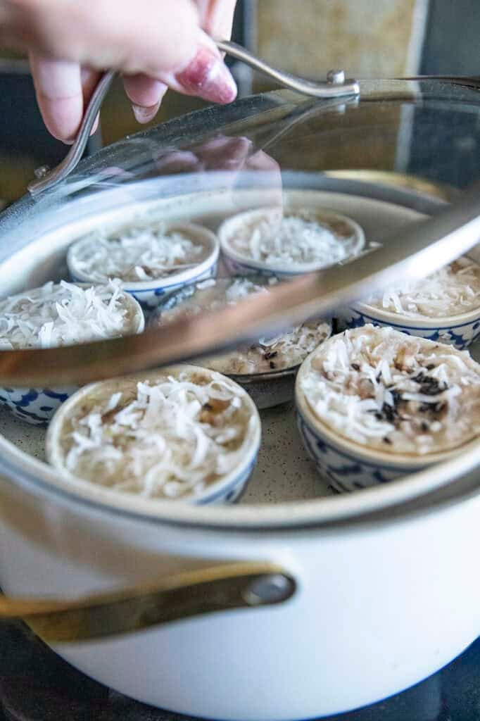 Thai banana desserts steaming in small ceramic cups.