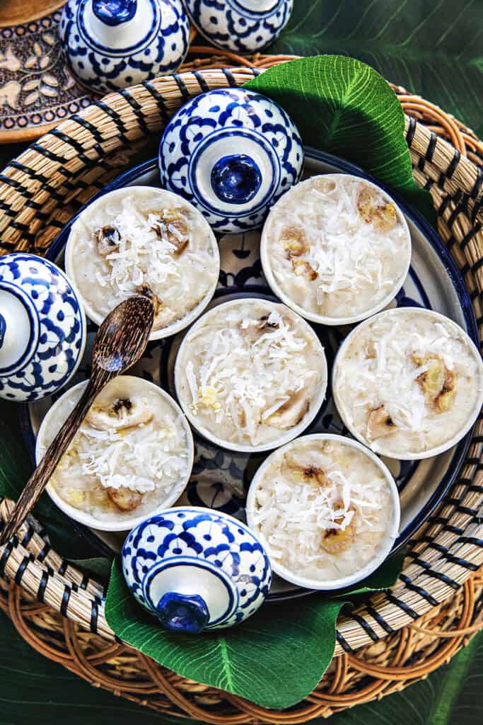 Khanom Kluay Thai steamed banana dessert in small thai pottery pieces topped with shredded coconut.